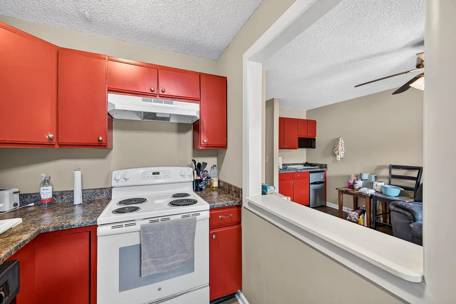 Kitchen at 1319 Bradley Dr with red cabinetry, a pass-through window to the living room, and tile floor