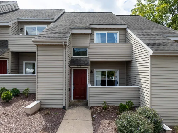 Front of 1319 Bradley Dr in Harrisonburg, a two-story townhouse with tan siding, a red front door, and a covered patio, in the Camden Townes community
