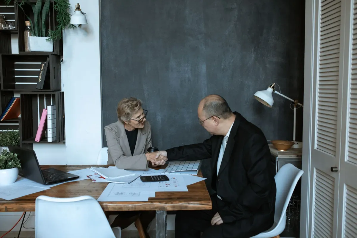 A handshake across a desk in a modern office.