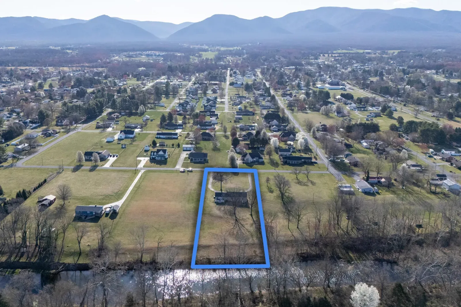 Aerial view of the 1.5-acre lot at 901 Riverside Ave in Grottoes, outlined, with the South River along the back and the Blue Ridge in the distance