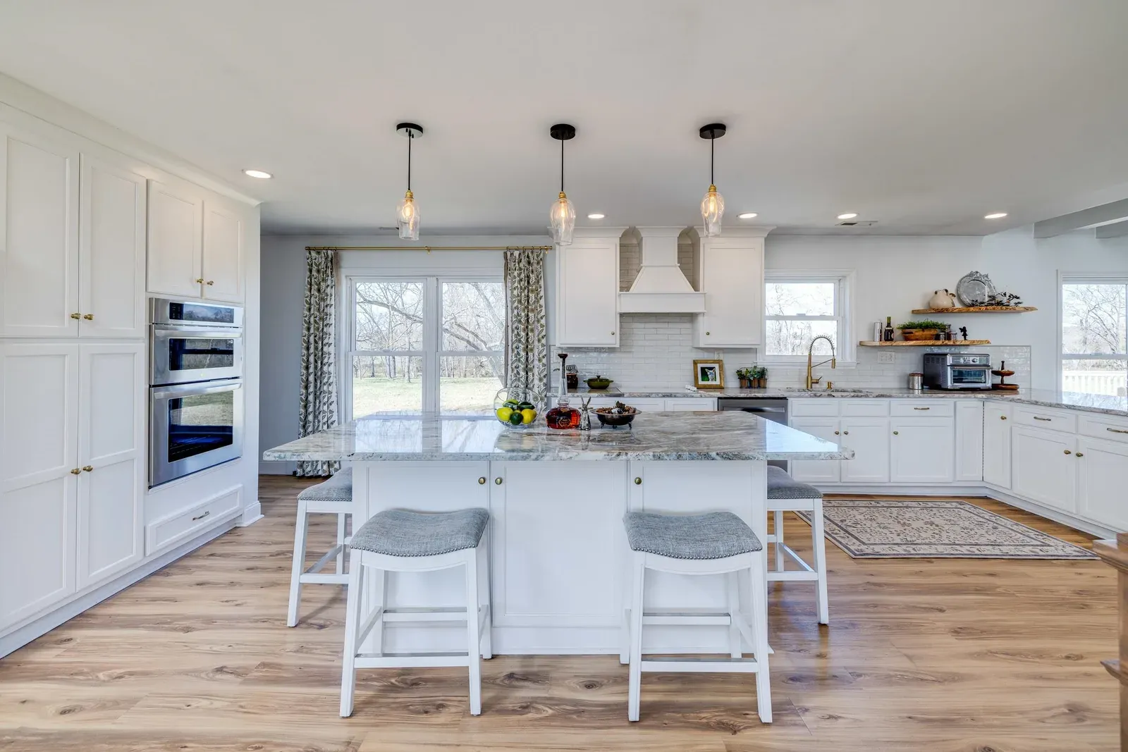Kitchen at 901 Riverside Ave with white cabinetry, double wall ovens, and a long granite island with seating