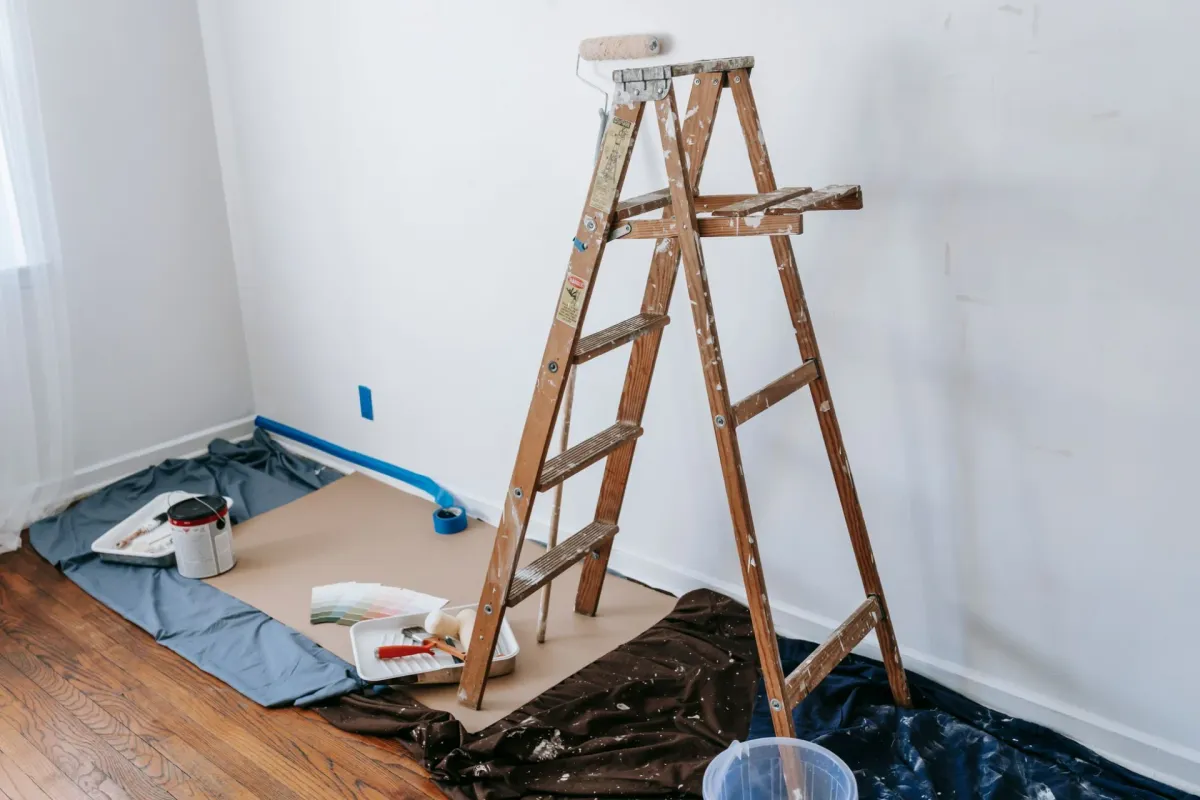 A room under renovation with a wooden ladder and paint supplies.