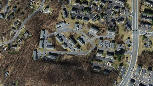 Aerial view of the Hillmont Circle area in southeast Harrisonburg, showing existing apartment buildings, townhouse rows, and wooded land around the site