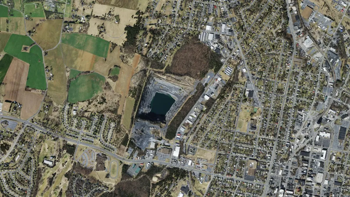Aerial view of the Waterman Drive quarry in Harrisonburg, with the water-filled pit in the center, farmland to the west, and the Park View and downtown neighborhoods to the east