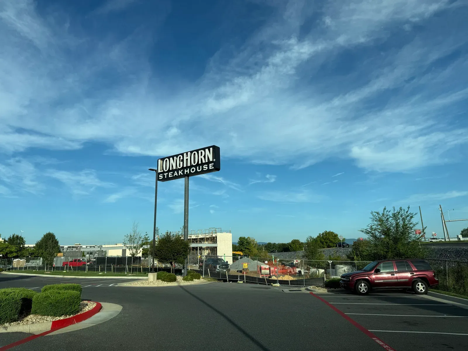 The Discount Tire site on Burgess Road seen from the LongHorn Steakhouse parking lot, with block walls, steel beams, and scaffolding up