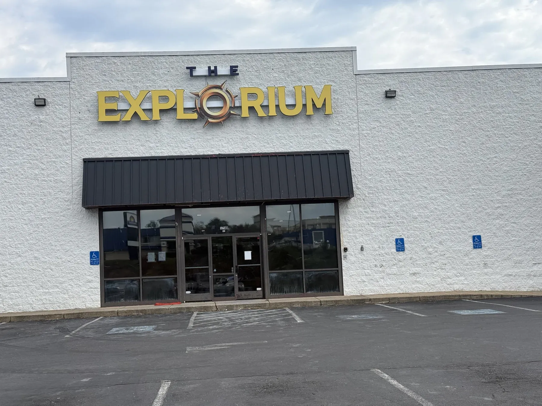 Close view of The Explorium sign on the white block building at 1740 E Market St, with the entrance below it and the address 1740 on the door