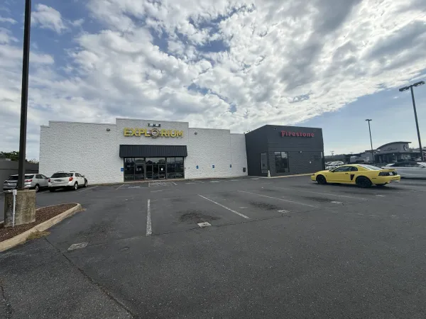 The Explorium sign already mounted on the white retail building at 1740 E Market St in Harrisonburg, with the Firestone store attached on the right