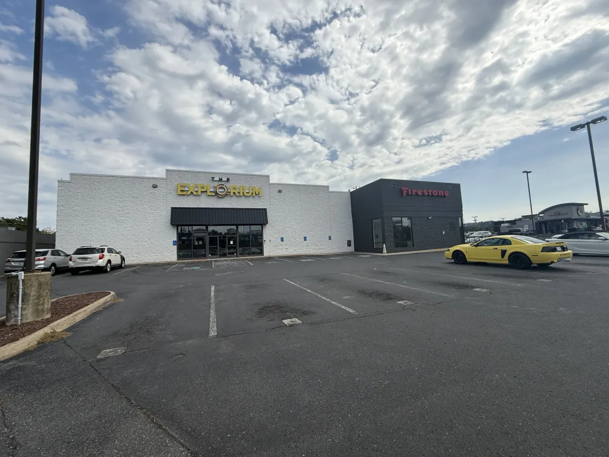 The Explorium sign already mounted on the white retail building at 1740 E Market St in Harrisonburg, with the Firestone store attached on the right